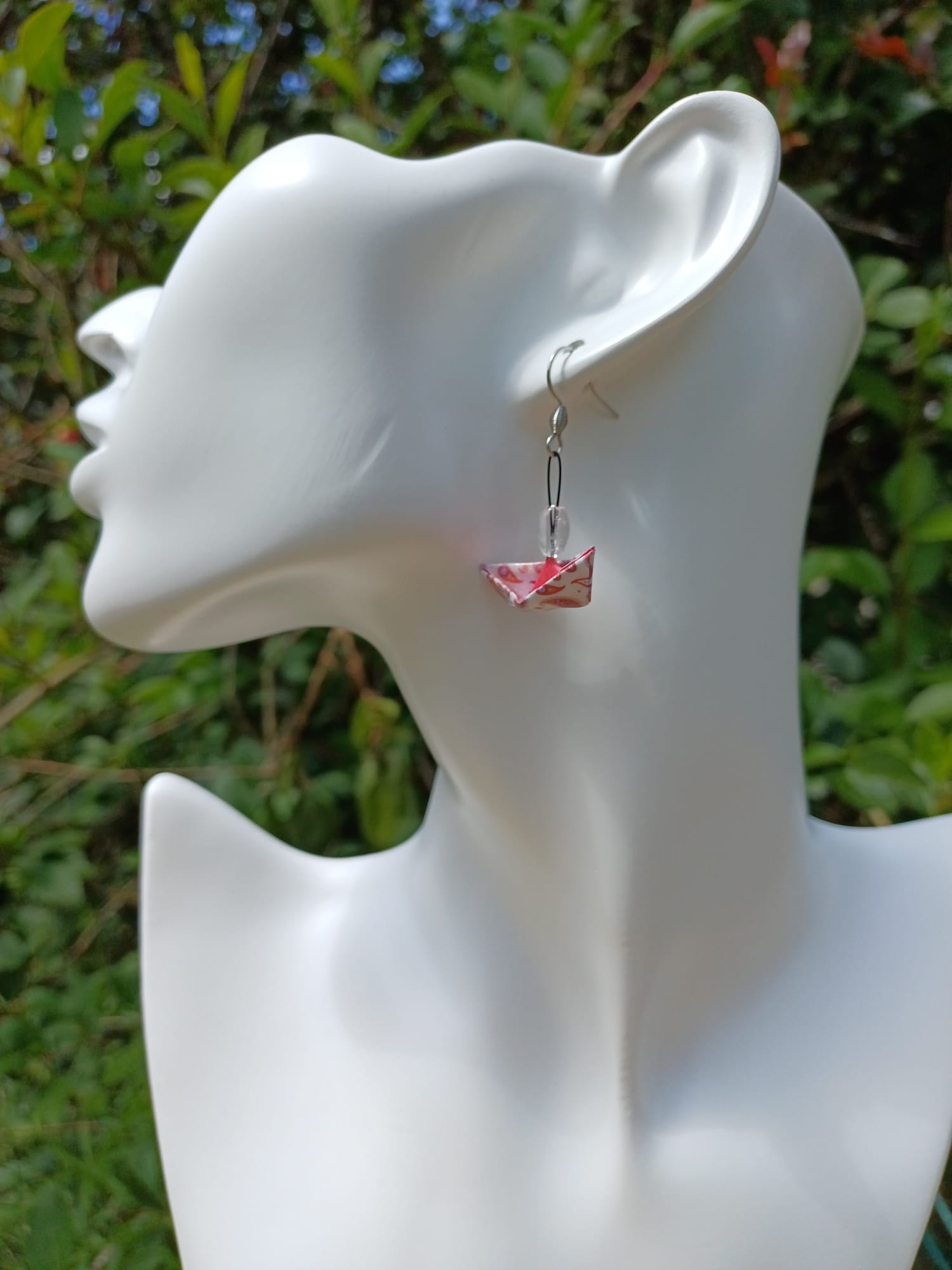 Boucles d'oreilles origami bateau rose paisley portées sur mannequin bijou fond végétal
