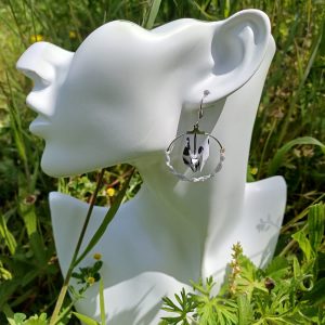 Boucles d'oreilles origami grue dalmatienne noir et blanc dans créole macramé blanc, portées sur mannequin fond prairie