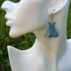 Boucles d'oreilles origami petite robe bleue turquoise portées sur mannequin bijou, fond jardin.