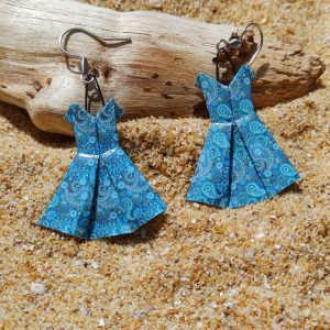 Paire de boucles d'oreilles origami petite robe bleue turquoise paisley posées sur sable doré avec bois flotté