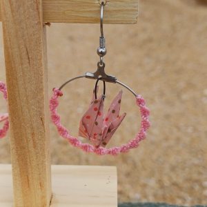 Boucle d'oreille origami en forme de grue rose à pois, cerceau enroulé de cordon rose, suspendue sur présentoir bois